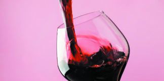 French dry red wine, pours into glass, trendy pink background