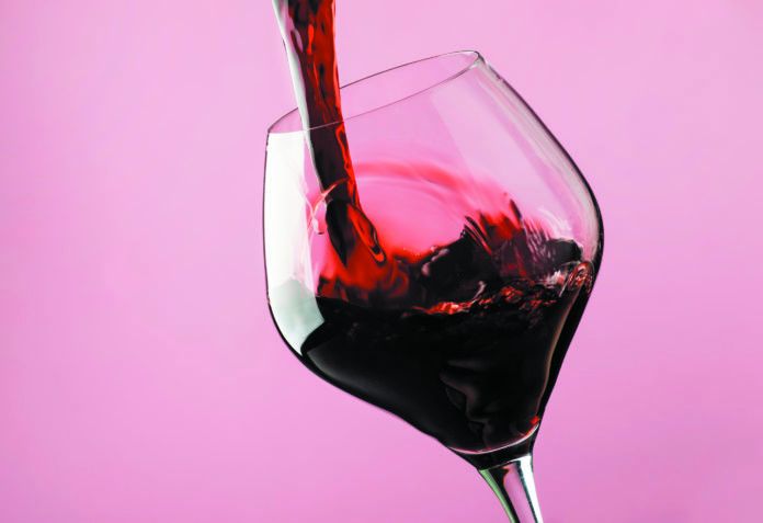 French dry red wine, pours into glass, trendy pink background