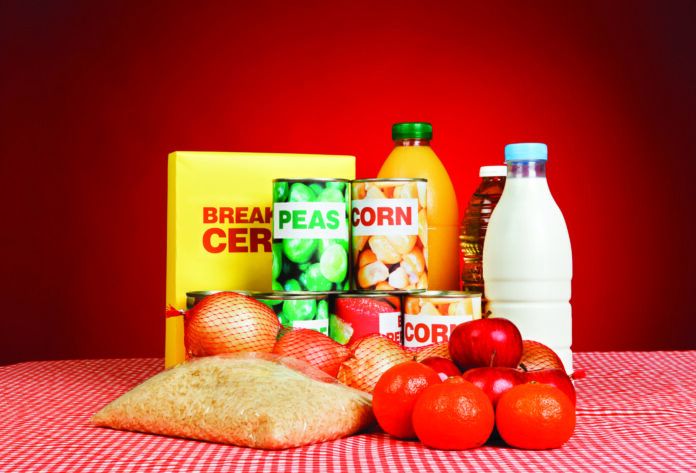 Variety of fresh and packaged basic foodstuffs against deep red