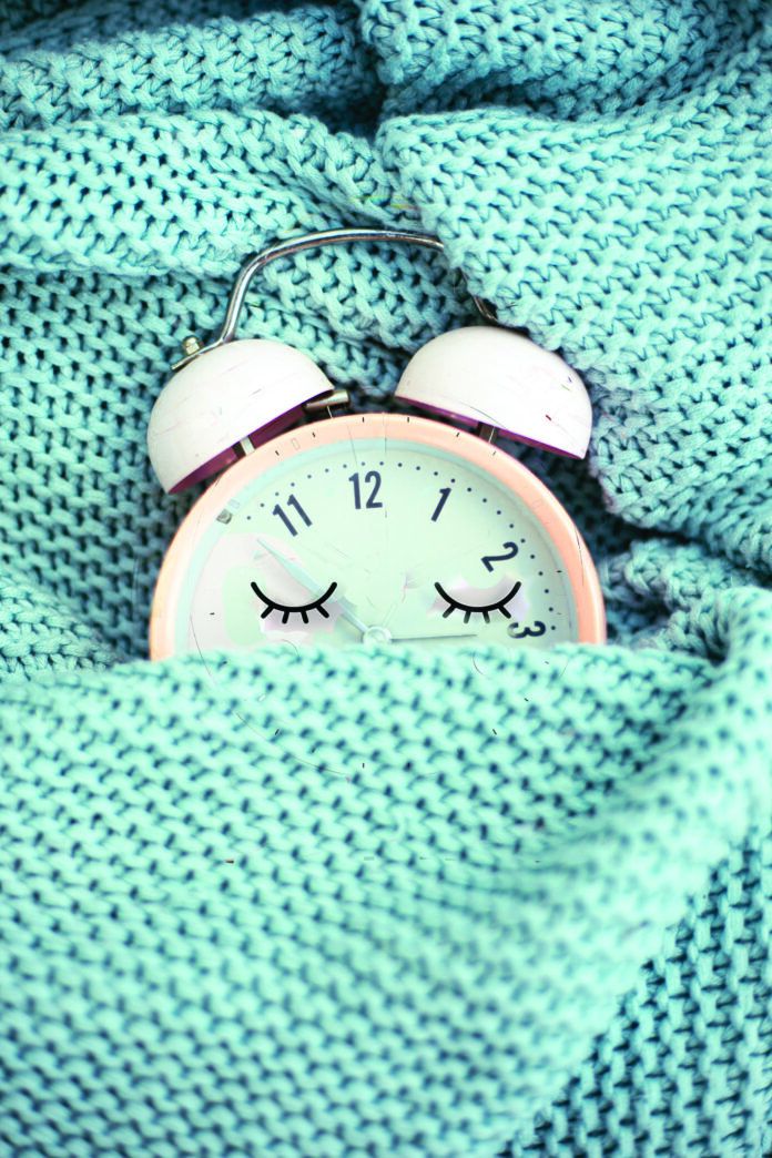 pink alarm clock sleeping in bed